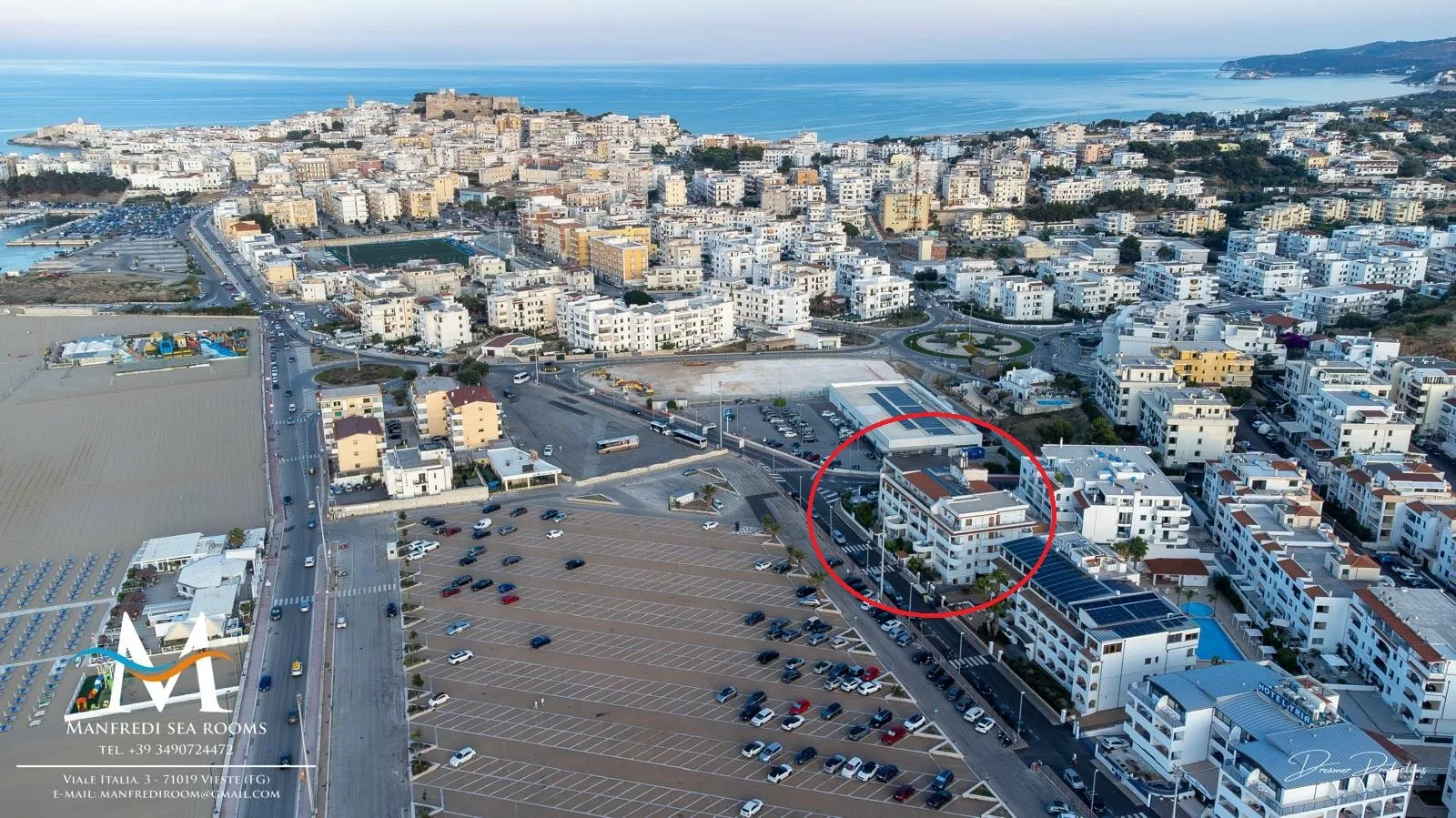 Vieste dall’alto: il grande parcheggio sul lungomare, i palazzi della città e il mare in fondo. La struttura è cerchiata in rosso