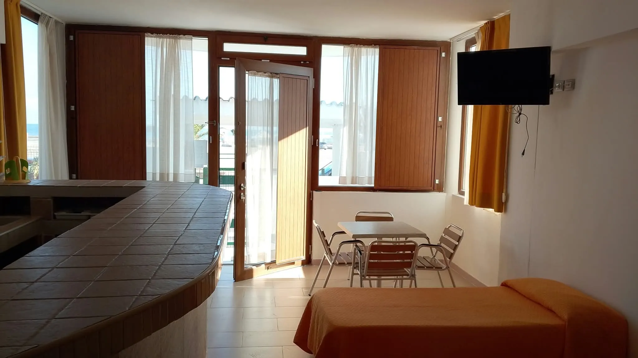 Appartamento 3a: il tavolo da pranzo, un letto e le porte finestre