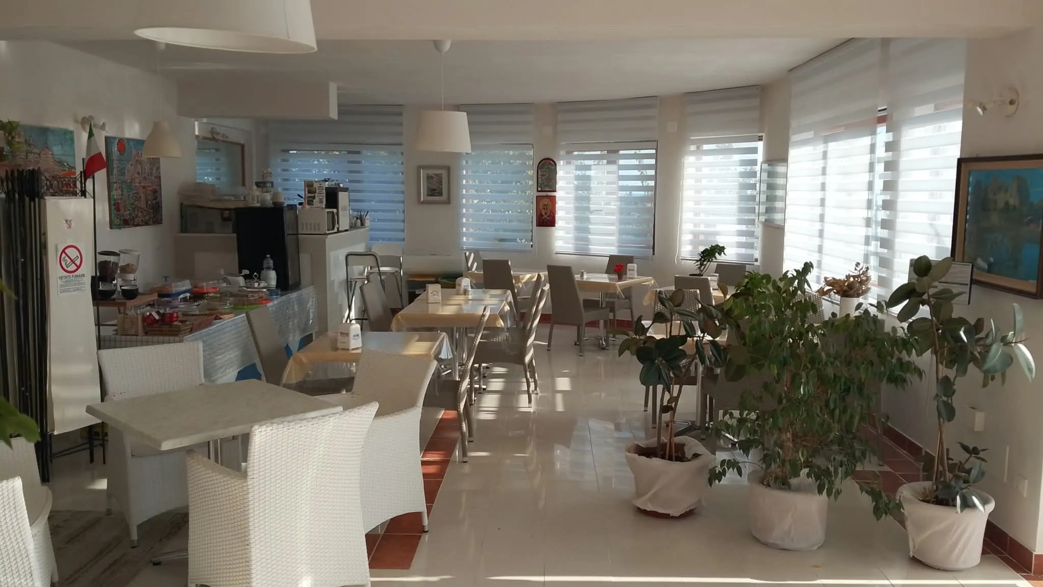 La sala colazione luminosa, con le piante e le finestre su due lati