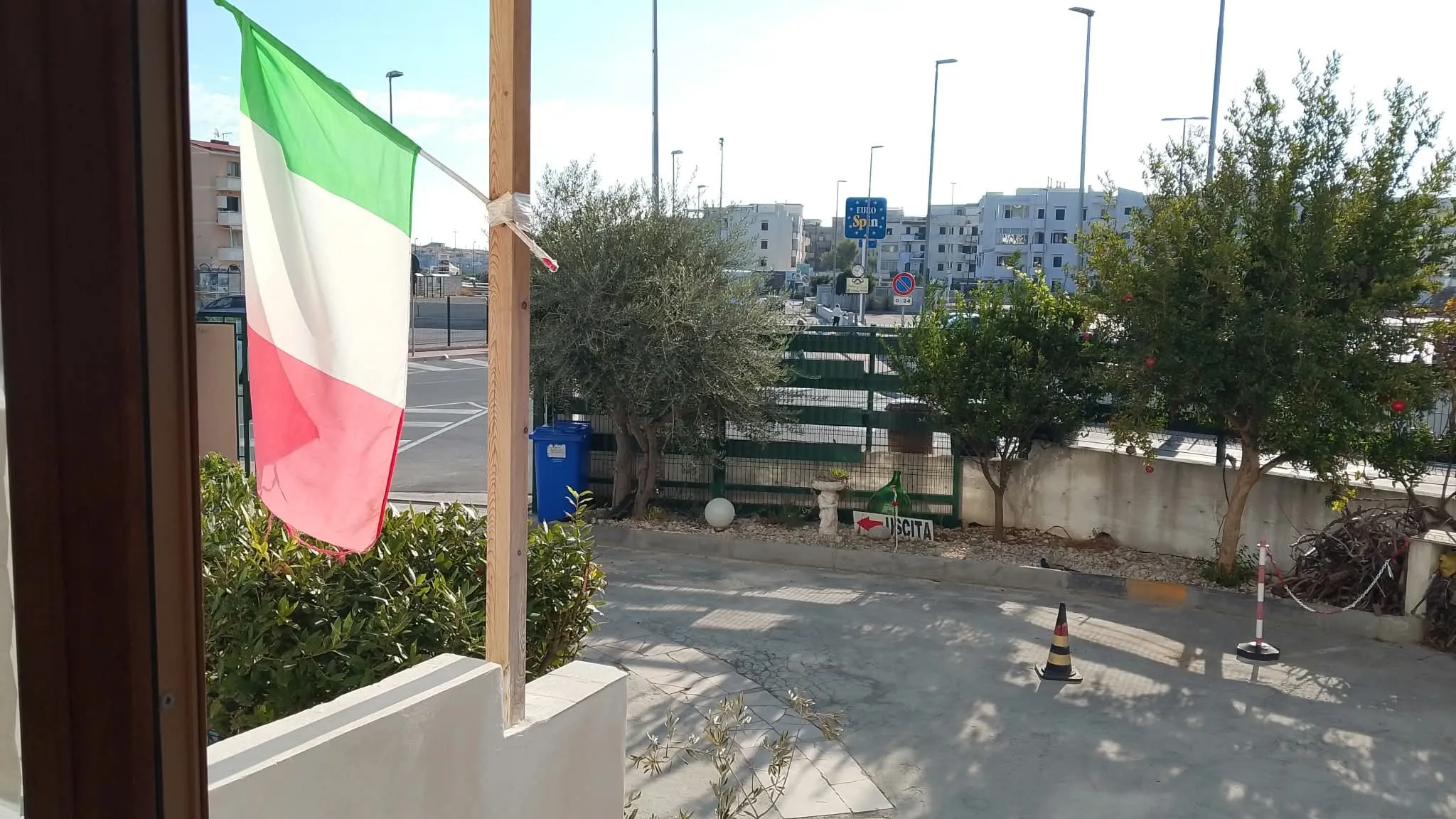 Dalla veranda: la bandiera, gli ulivi e il parcheggio